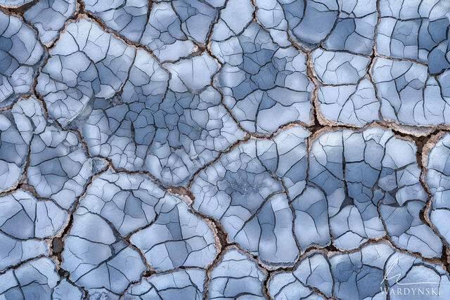 Contemporary fine art photograph of cracked mud tiles that are blue in hue.