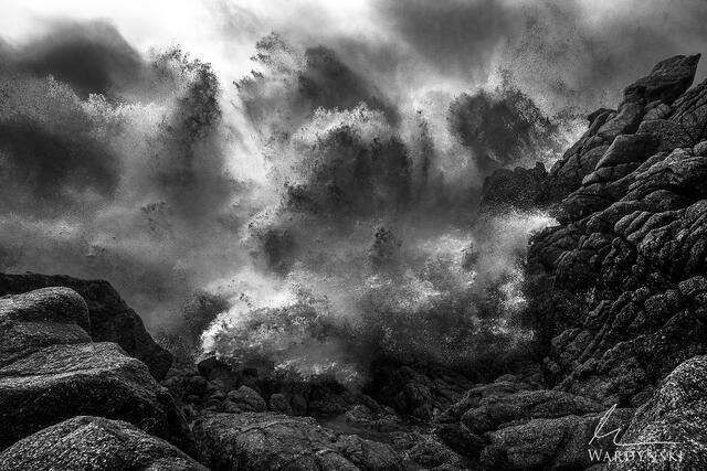Black and white photograph of a large wave as it crashes on the rocks in Big Sur California.